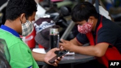 រូបឯកសារ៖ បុរសពីរនាក់ដែលមានពាក់ម៉ាស់ដើម្បីការពារការឆ្លងជំងឺកូវីដ១៩ កំពុងប្រើប្រាស់ប្រព័ន្ធអ៊ីនធឺណិតតាមទូរស័ព្ទស្មាតហ្វូន នៅរាជធានីភ្នំពេញ កាលពីថ្ងៃទី១៨ ខែមីនា ឆ្នាំ២០២០។