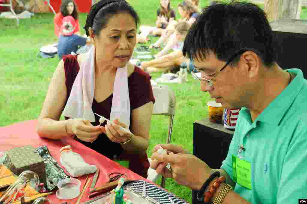 Artisans look over each others' work at the Smithsonian Folklife Festival in Washington, June 25, 2014. (Regina Catipon/VOA)