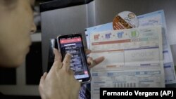 Tatiana Gomez shows how using her cell phone she pays a utility bill, in Bogota, Colombia, Tuesday, Nov. 10, 2020.(AP Photo/Fernando Vergara)