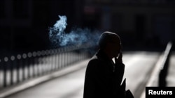 A man smokes a cigarette as he walks early morning in Frankfurt, Germany, Sept. 8, 2020.