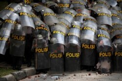 Police officers protect themselves with their shields during a protest against the new Job Creation Law, in Jakarta, Indonesia, Oct. 13, 2020.