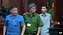 FILE - Australian man Chau Van Kham, left, is escorted into a court room in Ho Chi Minh city, Vietnam, Nov. 11, 2019. 