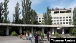 Visitors walk in the abandoned city of Pripyat, near the Chernobyl nuclear power plant