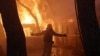 FILE - A firefighter reacts as a wildfire burns at Varympompi suburb north of Athens, Greece, August 3, 2021. 