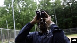 FILE - Keith Russell, program manager of urban conservation at Audubon Pennsylvania, looks through binoculars while conducting a breeding bird census, at Wissahickon Valley Park, June 5, 2020 in Philadelphia. 