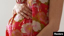 FILE - A woman holds her stomach at the last stages of her pregnancy in Bordeaux April 28, 2010. 