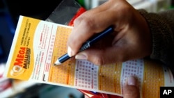 FILE - A customer picks numbers for a Mega Millions lottery ticket at a convenience store in Chicago.