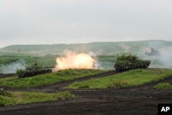 Tank Tipe-74 Pasukan Bela Diri Darat Jepang (JGSDF), kiri, menembakkan amunisi selama latihan tembakan di Area Manuver Fuji Timur di Gotemba, barat daya Tokyo, Sabtu, 22 Mei 2021. (Foto: via AP)