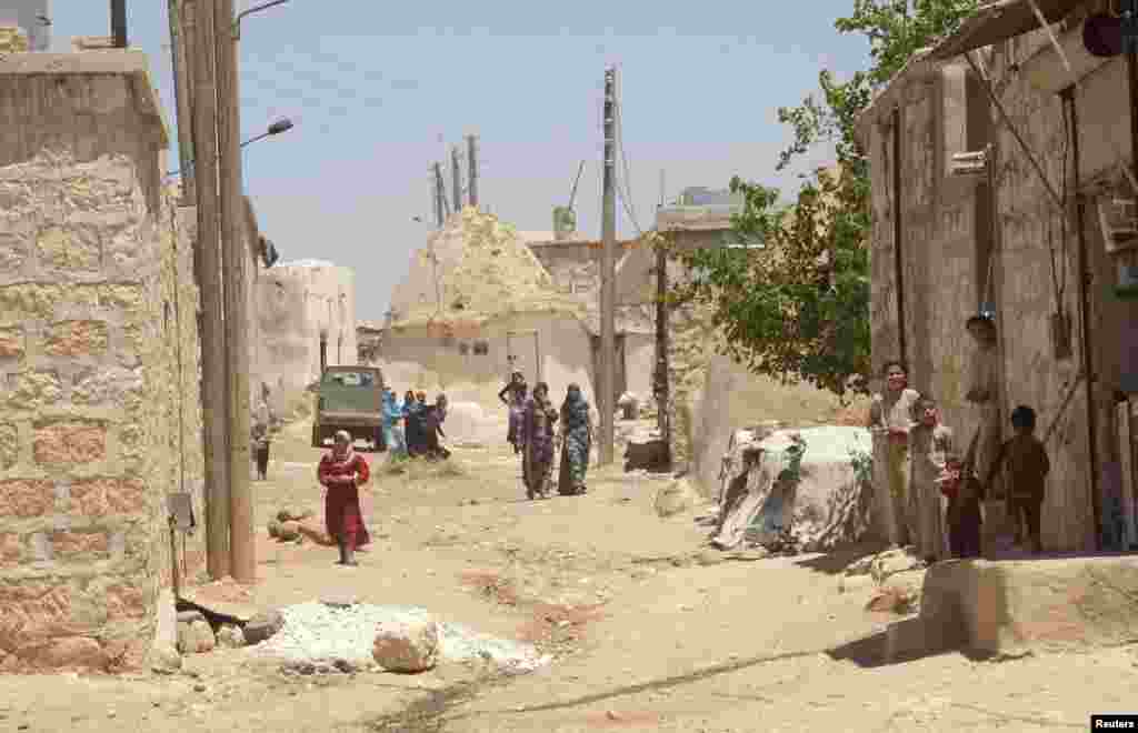 Residents are seen as forces loyal to Syria's President Bashar al-Assad enter Ain-Assan village outside Aleppo, Syria, June 15, 2013. 