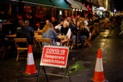 People drink at the outside tables of a cafe in Soho, in central London, Sept. 23, 2020.