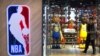 FILE - A man walks past statues of NBA players Stephen Curry of the Golden State Warriors, left, and Lebron James of the Los Angeles Lakers holding Chinese flags in the entrance of an NBA merchandise store in Beijing, Oct. 8, 2019.
