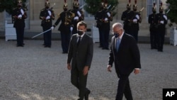 French President Emmanuel Macron, left, welcomes Australia's Prime Minister Scott Morrison before a working dinner in Paris, June 15, 2021.