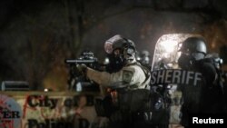 A police officer holds a tear gas launcher while standing guard at the Brooklyn Center Police Department, days after Daunte Wright was shot and killed by a police officer, in Brooklyn Center, Minnesota, April 13, 2021.