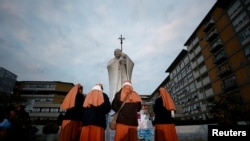 2025年3月8日，罗马杰梅利医院外，修女们聚集在临时纪念碑附近，教皇方济各正在那里接受双肺炎治疗。