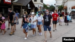 រូបឯកសារ៖ អ្នក​ទេសចរ​ដែលពាក់ម៉ាស់​​ដើម្បី​បង្ការ​ជំងឺ​កូវីដ១៩ ដើរ​កំសាន្តនៅក្នុង​​រមណីយដ្ឋាន Walt Disney World ក្រុង Lake Buena Vista រដ្ឋ Florida ថ្ងៃទី១១ ខែកក្កដា ឆ្នាំ២០២០។