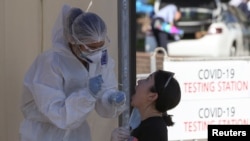 រូបឯកសារ៖ បុគ្គលិកផ្នែកសុខាភិបាលម្នាក់យកសំណាកពីស្រ្តីម្នាក់ ដើម្បីពិនិត្យរកជំងឺកូវីដ១៩ នៅក្រុង Almaty ប្រទេសកាហ្សាស្តង់ កាលពីថ្ងៃទី១៣ ខែកក្កដា ឆ្នាំ២០២០។ 