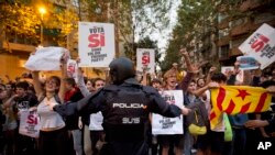 Seorang polisi Spanyol berusaha menghentikan demonstran yang menggelar aksi protes di luar kantor utama partai sayap kiri CUP di Barcelona, Spanyol, 20 September, 2017.