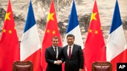 French President Emmanuel Macron, left, and Chinese President Xi Jinping shake hands after a joint press briefing at the Great Hall of the People in Beijing, Tuesday, Jan. 9, 2018.