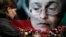 Seorang perempuan tampak meletakkan bunga di depan foto jurnalis Anna Politkovskaya, di Moskow, pada 7 Oktober 2009. Politkovskaya tewas dibunuh karena liputannya yang kritis terhadap Kremlin. (Foto: AP/Pavel Golovkin)