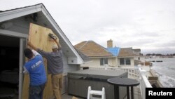 Warga di Milford, negara bagian Connecticut melindungi kaca-kaca di rumahnya dengan triplek untuk antisipasi datangnya badai super 'Sandy' (28/10). 