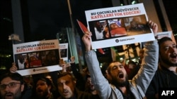 18일 튀르키예 이스탄불 주재 이스라엘 총영사관 인근에서 시위대가 팔레스타인 어린이 부상자들의 사진을 들고 구호를 외치고 있다. 