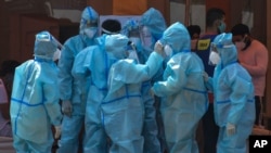 Health workers and volunteers in personal protective suits wait to receive patients outside a COVID-19 hospital that was set up at a Sikh Gurdwara (Temple) in New Delhi, India, May 10, 2021. 