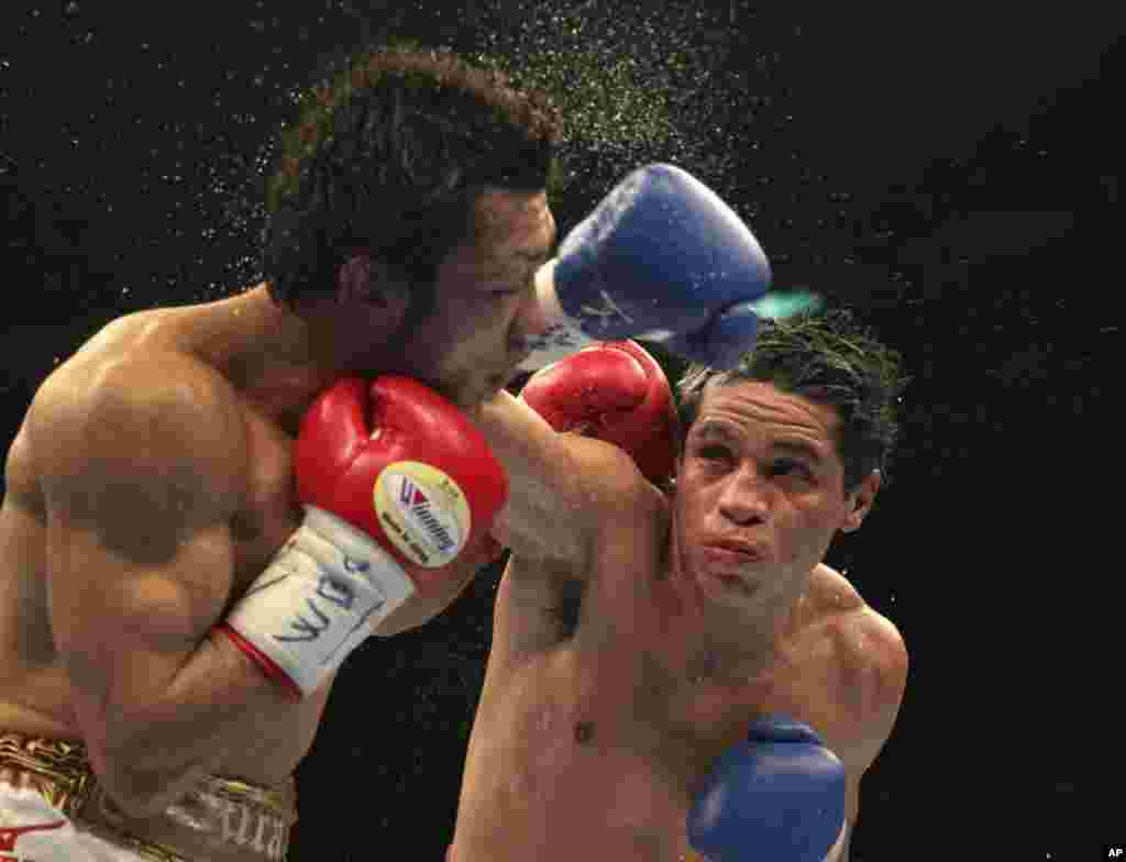 Petinju Jepang Akira Yaegashi, kiri, menerima pukulan dari penantangnya petinju Meksiko Edgar Sosa di babak ke-10 pertarungan tinju kelas terbang WBC di Tokyo. Yaegashi mempertahankan gelar dunianya dengan kemenangan telak.