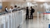 An American Airlines ticketing agent helps a woman as she approaches the counter in Denver International Airport as travelers deal with the effects of the new coronavirus, June 10, 2020, in Denver. 