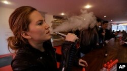 FILE - Talia Eisenberg, co-founder of the Henley Vaporium, uses her vaping device in New York, Feb. 20, 2014. 