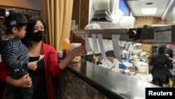 Owner Jan-le Low holds nephew Jackson Low as she moves order tickets at Satay Thai Bistro and Bar, amid the coronavirus disease (COVID-19) outbreak, in Las Vegas, Nevada, U.S., March 28, 2021. REUTERS/Bridget Bennett