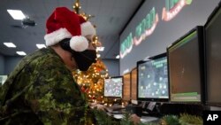 ເຈົ້າໜ້າທີ່ NORAD ລົມກັບຜູ້ທີ່ປາຍສາຍໂທລະສັບທີ່ຕິດຕາມ ແຊນຕ້າ ຄລອດສ໌ (Sable Brown/NORAD via AP)