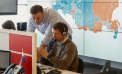 FILE - Opposition leader Alexei Navalny, standing, is seen at the office of his Anti-Corruption Foundation (FBK) in Moscow, Russia, March 18, 2018.