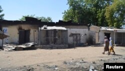 Dua perempuan Nigeria melewati rumah-rumah yang hangus akibat serangan militan Boko Haram bulan lalu (foto: dok). 