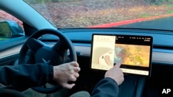 FILE - Vince Patton, a new Tesla owner, demonstrates on Dec. 8, 2021, on a closed course in Portland, Ore., how he can play video games on the vehicle's console while driving.