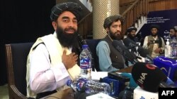 Juru bicara Taliban Zabihullah Mujahid (kiri) siap memberikan konferensi pers bertama setelah Taliban mengambil alih kekuasaan di Kabul, Afghanistan, Selasa (17/8). 