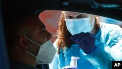 FILE - Nurse practitioner Marna Taylor gives Ahmad Bazzi a nasal swab to test for COVID-19 at ACCESS in Dearborn, Mich., June 12, 2020.