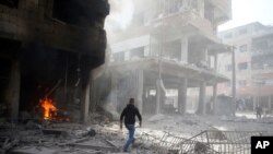 រូបឯកសារ៖ បុរស​ម្នាក់​ដើរ​នៅ​លើ​គំនរ​អាគារ​បាក់​បែក​ក្រោយ​ពេល​មាន​ការ​វាយ​ប្រហារ​តាម​អាកាស​នៅ​ទីក្រុង Douma នៃ​តំបន់ Ghouta​ ខាង​កើត ក្នុង​ប្រទេសស៊ីរី កាល​ពី​ខែ​កុម្ភៈ ២០១៨។