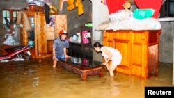 Residents move their belongings in a flooded house to higher ground in Vietnam's central province of Quang Binh October 18, 2011.