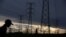 FILE - Men walk past electricity pylons as they return from work in Orlando, Soweto township, South Africa, March 18, 2019. 