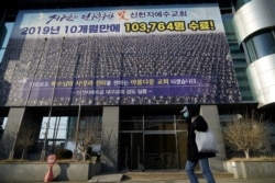 FILE - A man wearing a mask to prevent contracting the coronavirus walks past a branch of the Shincheonji Church of Jesus the Temple of the Tabernacle of the Testimony in Daegu, South Korea, Feb. 21, 2020.
