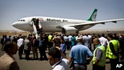 FILE - Yemeni airport, security and transportation officials greet a plane from the Iranian private airline, Mahan Air after it lands at the international airport in Sana'a, Yemen, March 1, 2015. 