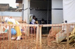FILE - A woman whose 5-year-old daughter was ill with her in an Ebola transit center where potential cases are evaluated, after being transported there by motorcycle taxi driver Germain Kalubenge, in Beni, Congo, Aug. 22, 2019.