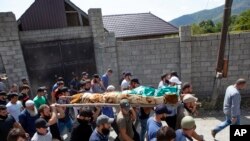 People carry the body of the victim who has been identified as Zelimkhan Khangoshvili, a Georgian Muslim who fought against Russia in the Second Chechen War during the funeral in Duisi village, the Pankisi Gorge valley, in Georgia, Aug. 29, 2019.