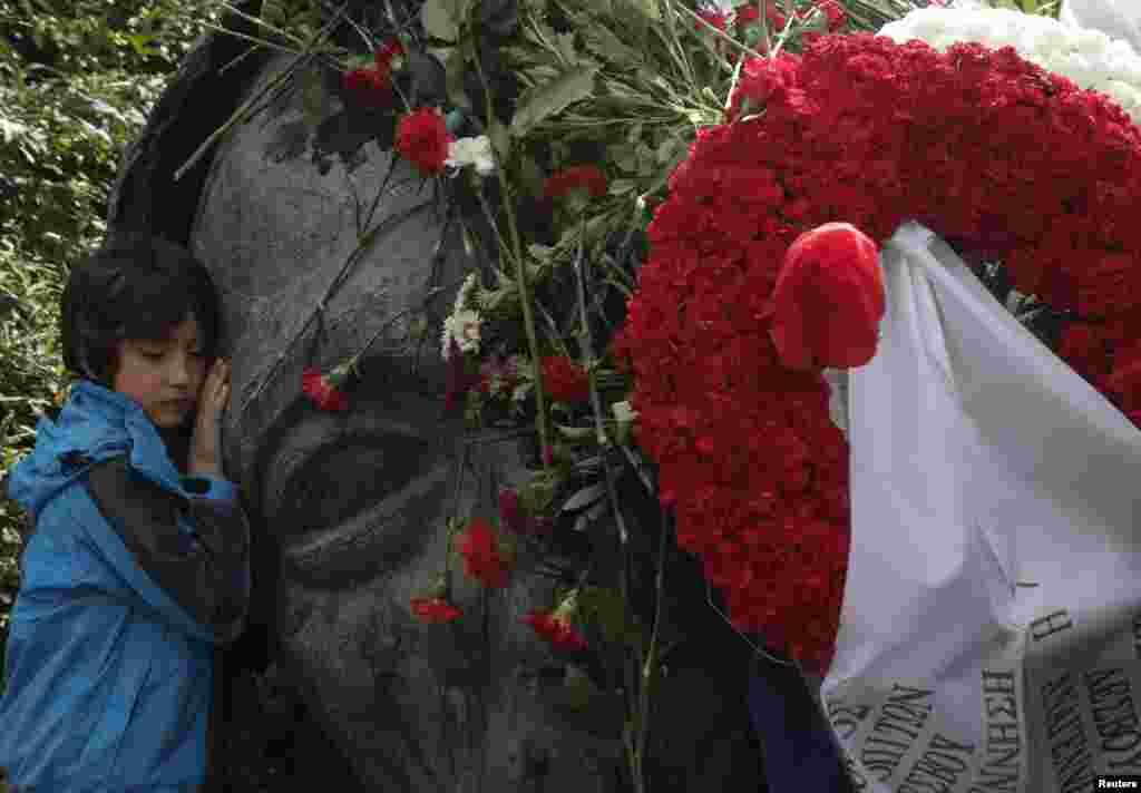 Seorang anak laki-laki memeluk sebuah monumen di dalam sekolah Politeknik Athena, dua hari sebelum peringatan ulang tahun pemberontakan mahasiswa tahun 1973 melawan junta militer yang berkuasa ketika itu, di Athena, Yunani. 