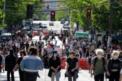People walk past barricades on a street near Cal Anderson Park, Thursday, June 11, 2020, inside what is being called the "Capitol Hill Autonomous Zone" in Seattle. Following days of violent confrontations with protesters, police have largely…