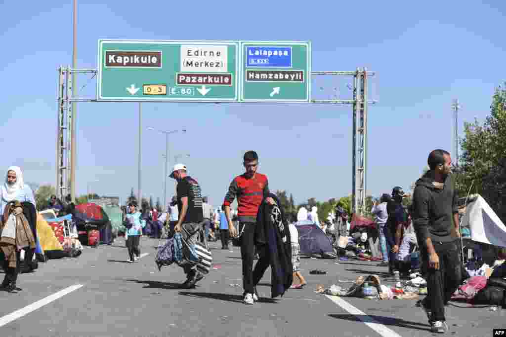 Migrants and refugees walk around tents as they wait after Turkish police forces block them on a highway near Edirn during their march to the border between Turkey and Greece.