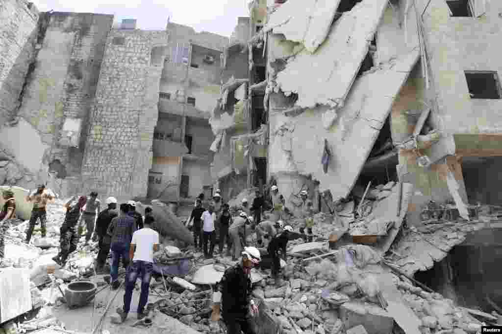 Rescue workers, rebel fighters and civilians search for survivors at a site hit by what activists said was a barrel bomb dropped by forces loyal to President Bashar al-Assad, al-Qarlaq, Aleppo, May 29, 2014.