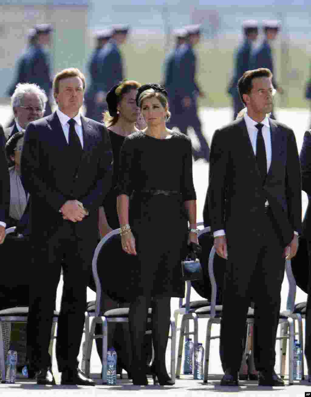 King Willem-Alexander, left, Queen Maxima and Prime Minister Mark Rutte, right, observe a minute of silence during a ceremony to mark the return of the first bodies of passengers and crew killed in the downing of Malaysia Airlines Flight 17, Eindhoven, Netherlands, July 23, 2014.