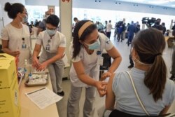 A health worker is inoculated with a COVID vaccine at the Clinicas Hospital in Sao Paulo, Brazil, Jan. 18, 2021.