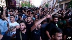 Shiite Hezbollah and Amal Movement groups stand in front of Lebanese army as they shout slogans against anti-government protesters, in downtown Beirut, Lebanon, Saturday, June 6, 2020. 